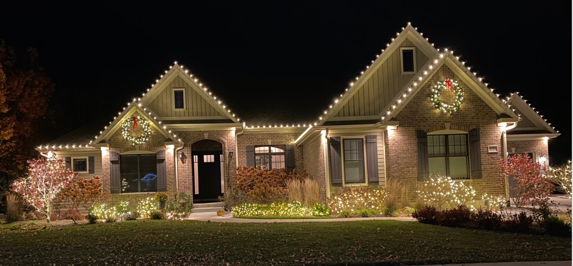 Craftsman home with warm white roofline lights and lit landscaping