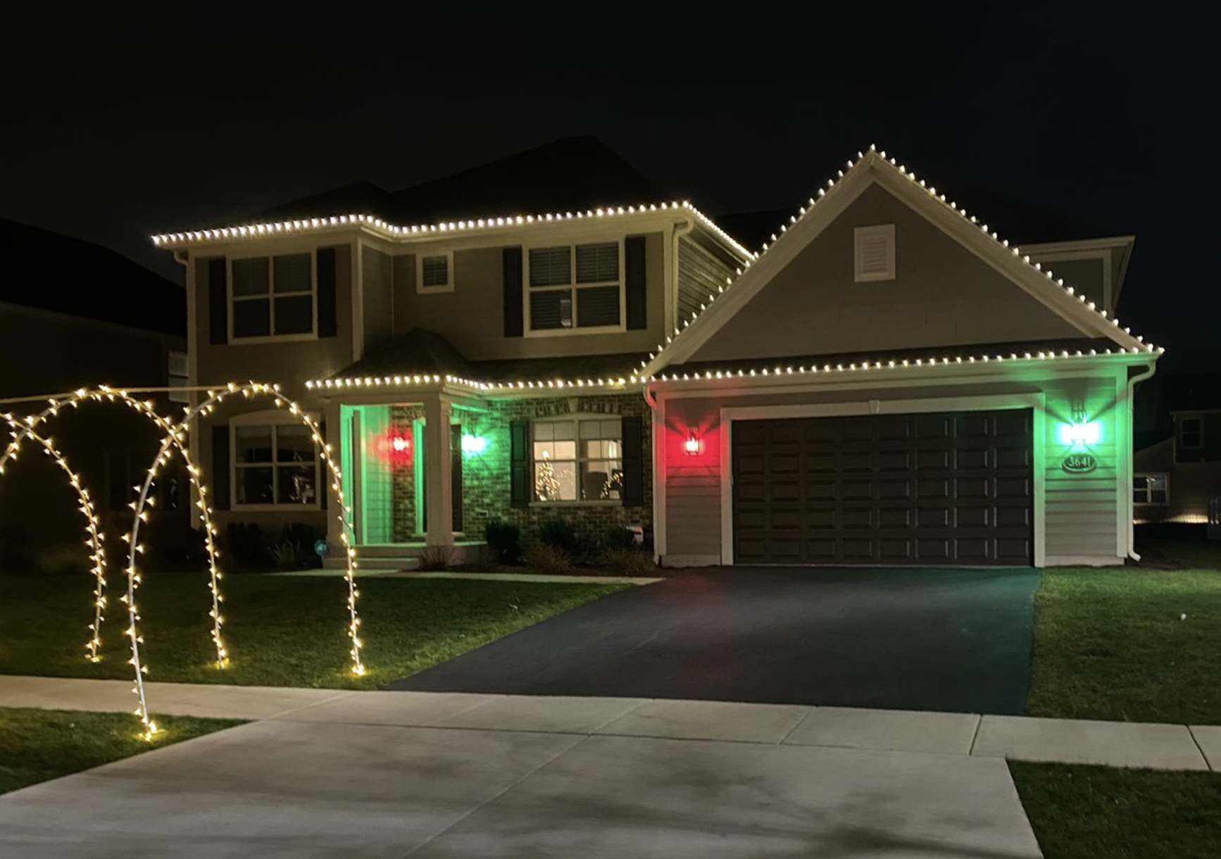 Two-story home with roofline lights and red and green accent lighting